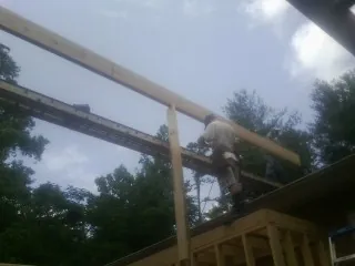 Carpenter setting a ridge beam over a new addition frame — Ice Dam Removal by Roofing Brothers in Carsonville