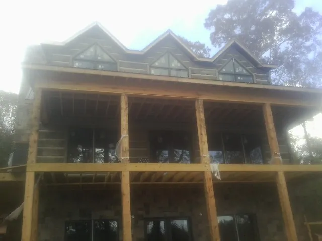 Dormers and porch framing on a large log home under construction — Roof Coating work by our crew in Carsonville