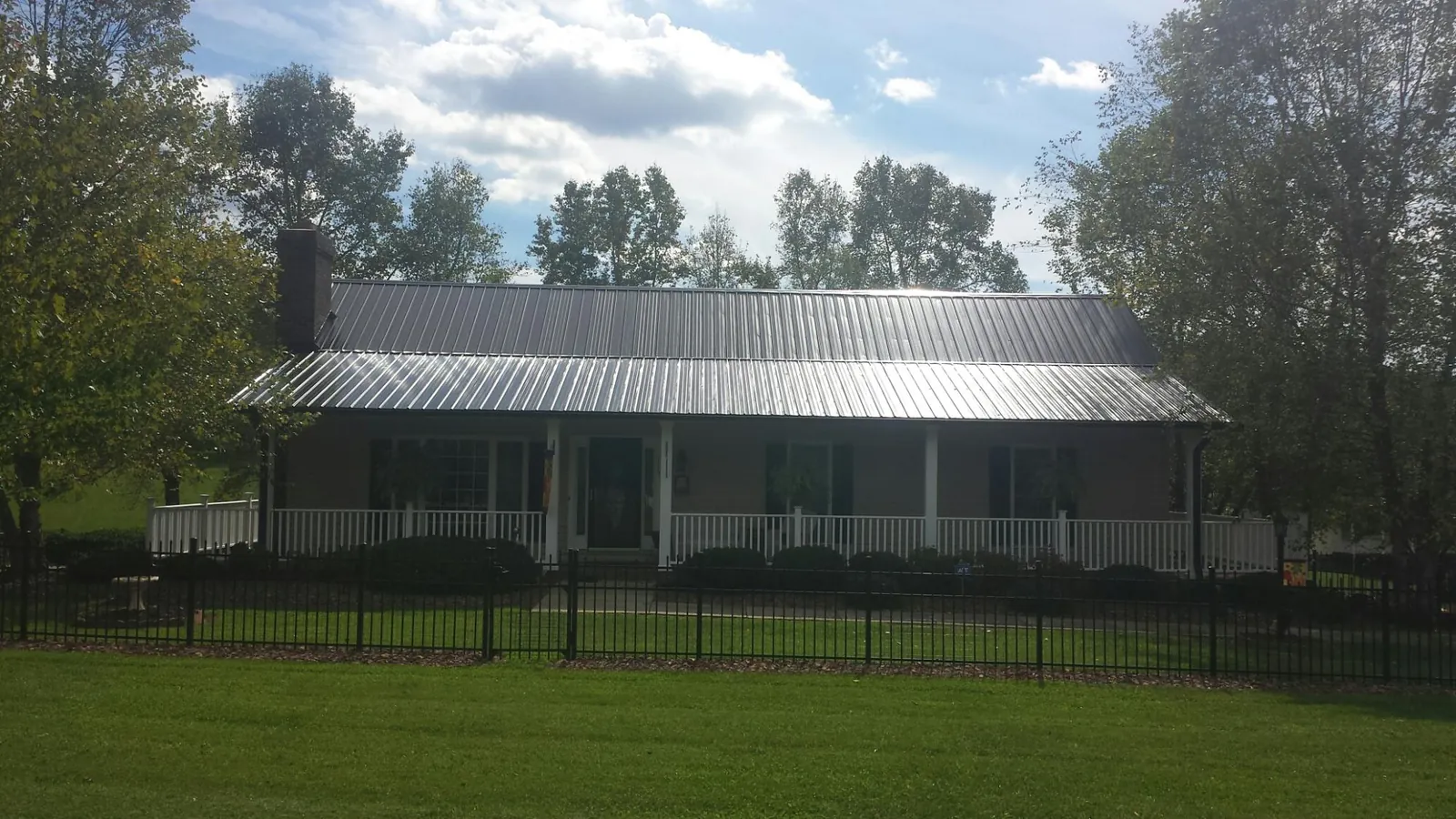Gray metal roof on a brick ranch with a full width front porch — Gutter Guard Installation work by our crew in Carsonville