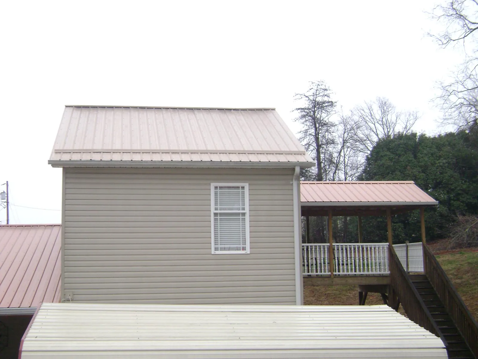 Tan metal roofs on a two story addition and attached porch, from a Roof Replacement job in Carsonville