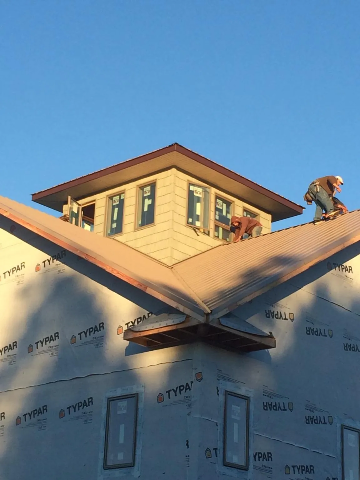 Roofers working around a rooftop cupola on a new metal roof at sunset — Roof Waterproofing in Carsonville by Roofing Brothers